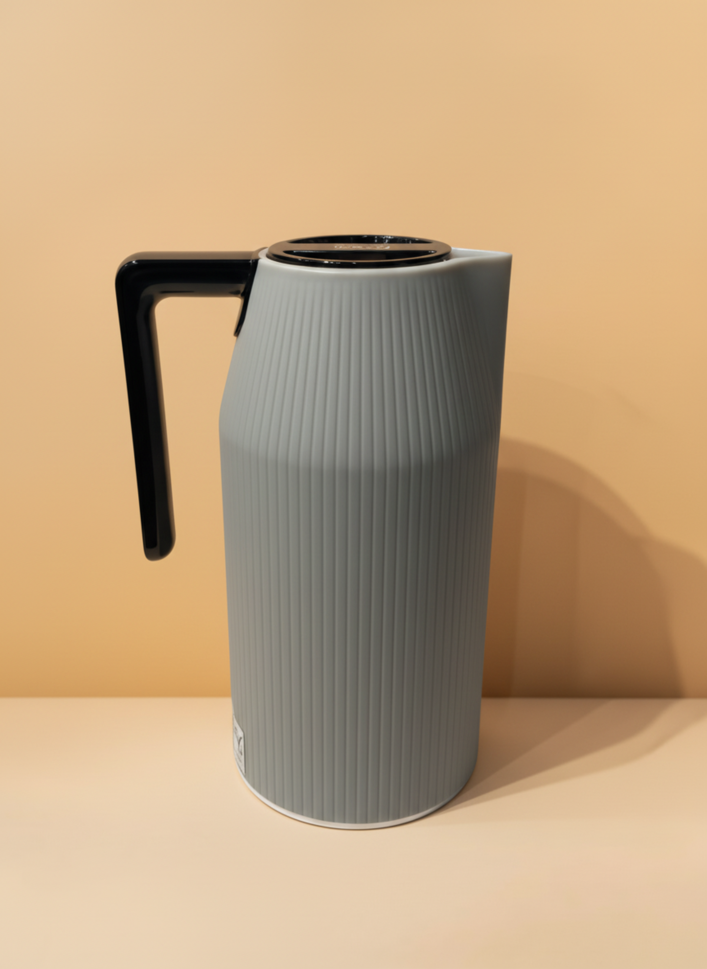 Gray pitcher with a black handle on a beige background