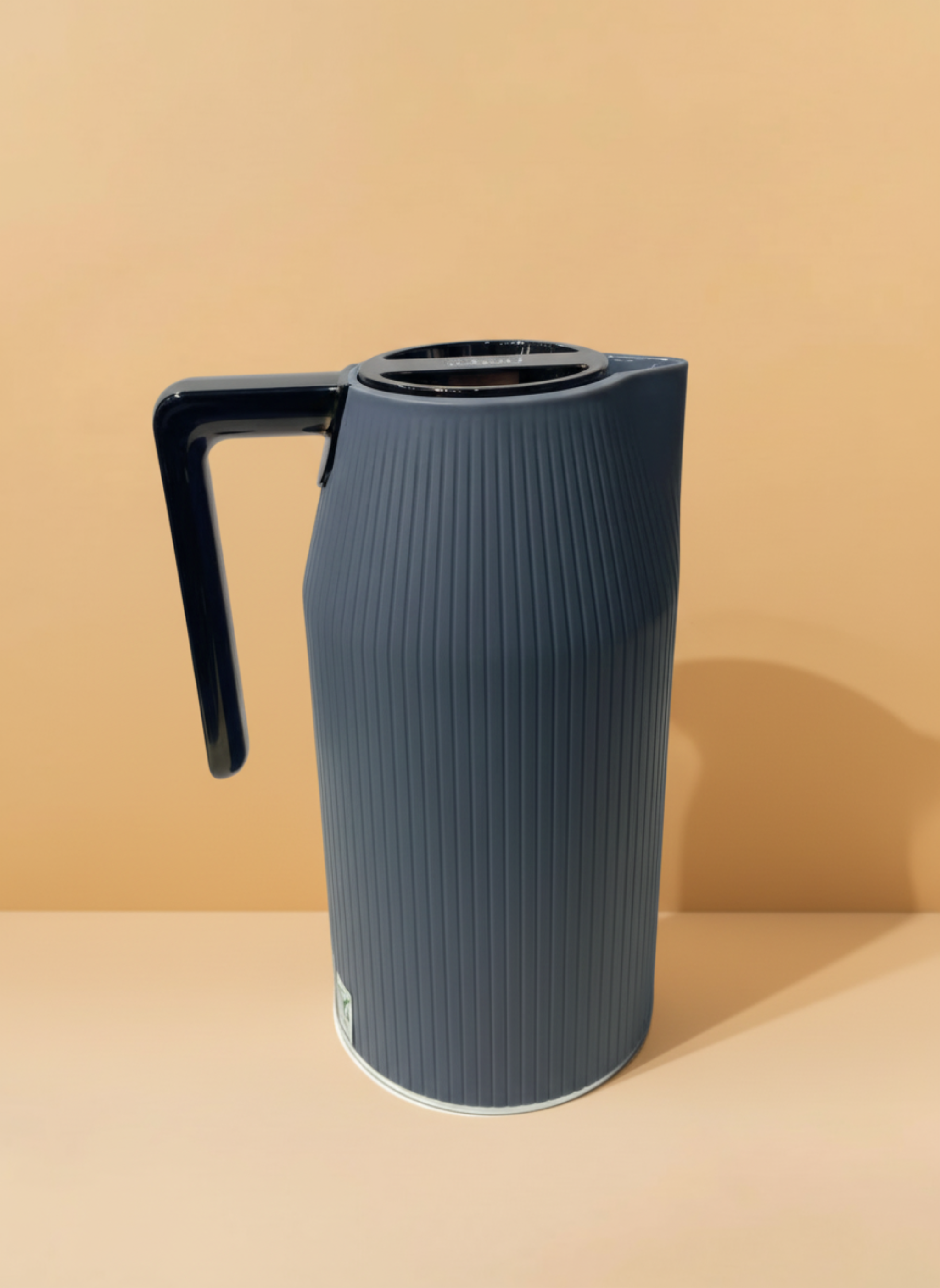 Dark blue textured pitcher with a black handle on a beige background